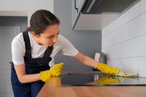 Professional cleaner scrubbing the kitchen cooktop.