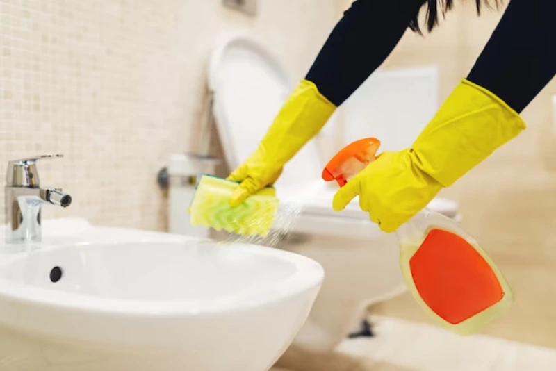cleaner scrubbing bathroom tiles and disinfecting sink